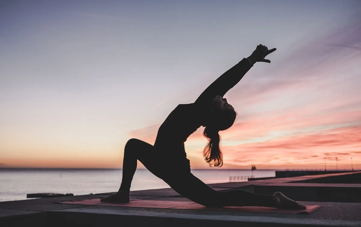 A person in a deep mobility lunge at sunset